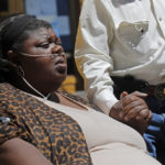 
              FILE - Kimberly Mcglothen, widow of Tommie McGlothen, Jr., holds the hand of his father, Tommie McGlothen, Sr., during a news conference with an attorney outside the Caddo Parish Courthouse in Shreveport, La., on  June 10, 2020. The trial of four officers charged in connection with the death of McGlothen, a man who died in police custody in northern Louisiana, will go forward, a judge ruled Thursday, Feb. 3, 2022, rejecting efforts by the four Shreveport officers to have the charges thrown out. (AP Photo/Gerald Herbert, File)
            