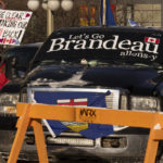 
              A protester walks past a truck parked in the street in the downtown core during a demonstration against COVID-19 restrictions, Saturday, Feb. 5, 2022, in Ottawa, Ontario. (Adrian Wyld/The Canadian Press via AP)
            