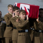 
              FILE - Soldiers carry the flag draped casket of World War I British Private Thomas Edmundson during a re-burial service at Perth Cemetery in Ypres, Belgium, March 14, 2018. In Belgium, bodies of World War I are still being found to this day, testimony to the brutality of four years of fighting in Flanders Fields. (AP Photo/Virginia Mayo, file)
            