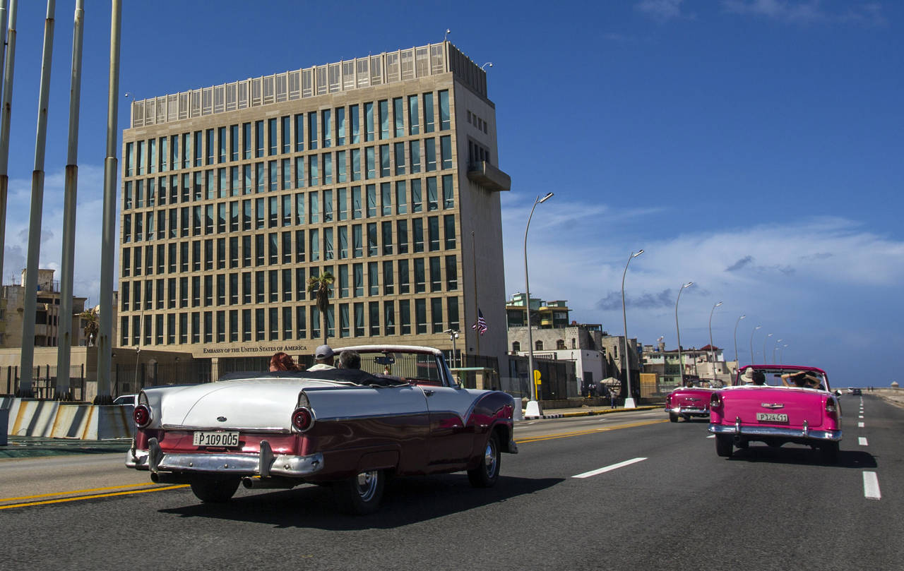 FILE - Tourists ride classic convertible cars on the Malecon beside the U.S. Embassy in Havana, Cub...