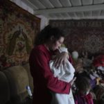 
              Anastasia Manha, 23, lulls her 2 month-old son Mykyta, where she lives with her family members, after alleged shelling by separatists forces in Novognativka, eastern Ukraine, Sunday, Feb. 20, 2022. Russia is extending military drills near Ukraine's northern borders after two days of sustained shelling along the contact line between Ukrainian soldiers and Russia-backed separatists in eastern Ukraine. The exercises in Belarus, which borders Ukraine to the north, originally were set to end on Sunday. (AP Photo/Evgeniy Maloletka)
            