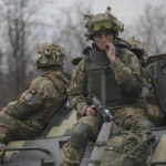 
              Ukrainian servicemen sit atop armored personnel carriers driving on a road in the Donetsk region, eastern Ukraine, Thursday, Feb. 24, 2022. Russian President Vladimir Putin on Thursday announced a military operation in Ukraine and warned other countries that any attempt to interfere with the Russian action would lead to "consequences you have never seen." (AP Photo/Vadim Ghirda)
            