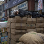 
              A laborer lies down atop goods ready for transportation at a wholesale market in New Delhi, India, Tuesday, Feb. 1, 2022. (AP Photo/Altaf Qadri)
            