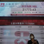 
              A woman walks past a bank's electronic board showing the Hong Kong share index in Hong Kong Tuesday, March, 29, 2022. Asian shares are higher after an advance on Wall Street ahead of another round of talks between Russia and Ukraine. (AP Photo/Vincent Yu)
            