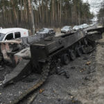 
              FILE - Cars drive past a destroyed Russian tank as a convoy of vehicles evacuating civilians leaves Irpin, on the outskirts of Kyiv, Ukraine, March 9, 2022. (AP Photo/Vadim Ghirda, File)
            