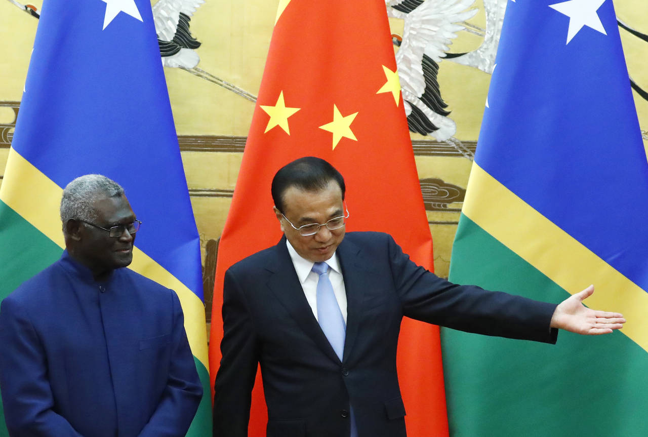 FILE - Solomon Islands Prime Minister Manasseh Sogavare, left, and Chinese Premier Li Keqiang atten...