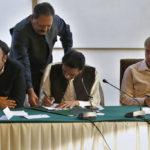 
              Leader of the Muttahida Qaumi Movement Khalid Maqbool Siddiqui, center, signs an agreement while opposition parties leaders Bilawal Bhutto Zardari, left, and Shahbaz Sharif, watch during a press conference, in Islamabad, Pakistan, Wednesday, March 30, 2022. Lawmakers appeared poised to push Prime Minister Imran Khan out of power in an upcoming no-confidence vote, after a small but key coalition partner abandoned him and joined the opposition. (AP Photo/Anjum Naveed)
            