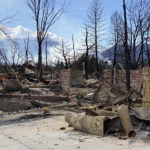
              This photo provided by realtor Alicia Miller shows the ruins of Miller's former house, which burned to the ground on Dec. 30, 2021, in the devastating Marshall Fire that roared through Louisville, Colo., as smoke from the NCAR Fire burns, Saturday, March 26, 2022, in the background. About 1,200 Colorado residents have been ordered to evacuate due to a fast-moving wildfire near the site of a destructive 2021 blaze, Boulder police said. (Alicia Miller via AP)
            