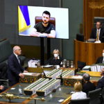 
              Australian Prime Minister Scott Morrison, standing, welcomes Ukrainian President Volodymyr Zelenskyy to address the House of Representatives via a video link at Parliament House in Canberra, Thursday, March 31, 2022. Zelenskyy appealed directly to Australian lawmakers for more help in its war against Russia including armored vehicles and tougher sanctions. (Lukas Coch/AAP Image via AP)
            