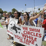 
              FILE - In this Sunday, Aug. 9, 2015 file photo, Barbara Fulchini, foreground, 24, of Miami, and Adriana Pruitt, center, 32, of Miramar, Fla., attempt to turn back people at the entrance to the Miami Seaquarium during a protest against Lolita the orca's decades-long captivity at the Miami Seaquarium in Miami. The new owners of the Miami Seaquarium will no longer stage shows with its aging orca Lolita under an agreement with federal regulators. MS Leisure, a subsidiary of The Dolphin Company, said in a news release it completed acquisition of the Seaquarium on Thursday, March 3, 2022.  (AP Photo/Wilfredo Lee, File)
            