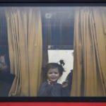 
              A child refugee fleeing the war from neighbouring Ukraine with her family looks out the window of a bus after crossing the border by ferry at the Isaccea-Orlivka border crossing, in Romania, Friday, March 25, 2022. (AP Photo/Andreea Alexandru)
            