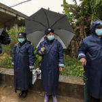 
              Police in rain gear stand watch along a road heading to Molang village near the crashed site of the China Eastern Flight 5735, Thursday, March 24, 2022, in southwestern China's Guangxi province. The search area was expanded Thursday in a "blanket search" for the second black box from a China Eastern passenger plane that crashed in southern China with 132 people on board earlier this week, state media said. (AP Photo/Ng Han Guan)
            