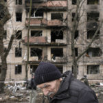 
              FILE - An elderly man walks outside an apartment block which was destroyed by an artillery strike in Kyiv, Ukraine, Monday, March 14, 2022. Ukrainian President Volodymyr Zelenskyy has pleaded with parliaments in the United States, the EU, Britain, Japan and Canada for more military and humanitarian aid. Yet his demands for NATO to enforce a no-fly zone to protect his people have fallen on deaf ears, with the alliance making clear it is not risking an all-out war with Russia. (AP Photo/Vadim Ghirda, File)
            