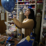 
              Karla Morales, of Revere, Mass., inflates balloons while working at her families' party supply shop, in the East Boston neighborhood of Boston, Sunday, March 27, 2022. Morales, who left El Salvador with her family when she was 3 years old, and has been on Temporary Protected Status, or TPS, nearly her whole life, says the status has allowed her family to work, build a successful small business and pay taxes but without providing a pathway to citizenship. (AP Photo/Steven Senne)
            