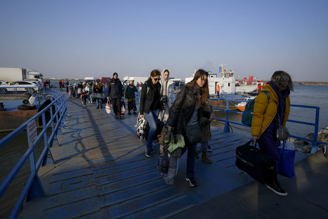 Refugees fleeing the war from neighbouring Ukraine walk after crossing the border by ferry at the I...
