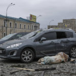 
              The body of a victim lies next to damaged cars in the central square following shelling of the City Hall building in Kharkiv, Ukraine, Tuesday, March 1, 2022. Russia on Tuesday stepped up shelling of Kharkiv, Ukraine's second-largest city, pounding civilian targets there. Casualties mounted and reports emerged that more than 70 Ukrainian soldiers were killed after Russian artillery recently hit a military base in Okhtyrka, a city between Kharkiv and Kyiv, the capital. (AP Photo/Pavel Dorogoy)
            