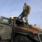 
              A Ukrainian soldier stands a top a destroyed Russian APC after recent battle in Kharkiv, Ukraine, Saturday, March 26, 2022. With Russia continuing to strike and encircle urban populations, from Chernihiv and Kharkiv in the north to Mariupol in the south, Ukrainian authorities said Saturday that they cannot trust statements from the Russian military Friday suggesting that the Kremlin planned to concentrate its remaining strength on wresting the entirety of Ukraine's eastern Donbas region from Ukrainian control. (AP Photo/Efrem Lukatsky)
            