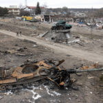 
              Local residents pass at a damaged Russian tank in the town of Trostsyanets, some 400km (250 miles) east of capital Kyiv, Ukraine, Monday, March 28, 2022. The monument to Second World War is seen in background. The more than month-old war has killed thousands and driven more than 10 million Ukrainians from their homes including almost 4 million from their country. (AP Photo/Efrem Lukatsky)
            