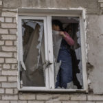 
              A woman places plastic over her damaged window after a Russian attack on the previous night, in the residential area of Mikolaiv, Ukraine, on Tuesday, March 29, 2022. (AP Photo/Petros Giannakouris)
            