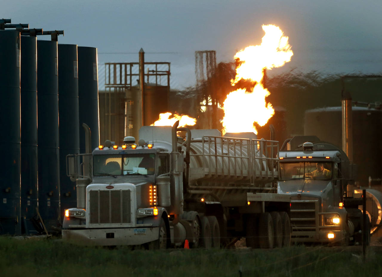 FILE - Drivers and their tanker trucks capable of hauling water and hydraulic fracturing liquid lin...