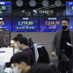 
              A currency trader moves past screens showing the Korea Composite Stock Price Index (KOSPI), center left, and the foreign exchange rate between U.S. dollar and South Korean won, center right, at the foreign exchange dealing room of the KEB Hana Bank headquarters in Seoul, South Korea, Thursday, March 24, 2022. Stocks slipped Thursday in Asia following a retreat on Wall Street as crude oil prices rose sharply.(AP Photo/Ahn Young-joon)
            