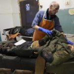 
              EDS NOTE: GRAPHIC CONTENT - A morgue worker looks at the body of killed volunteer of Ukraine's Territorial Defense Forces at a hospital in Brovary, outside Kyiv, Ukraine, Tuesday, March 1, 2022. Russian shelling pounded civilian targets in Ukraine's second-largest city again Tuesday and a 40-mile convoy of tanks and other vehicles threatened the capital — tactics Ukraine’s embattled president said were designed to force him into concessions in Europe’s largest ground war in generations. (AP Photo/Efrem Lukatsky)
            