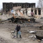 
              A local resident passes with his bicycle in front of damaged buildings and a tank in the town of Trostsyanets, some 400km (250 miles) east of capital Kyiv, Ukraine, Monday, March 28, 2022. The more than month-old war has killed thousands and driven more than 10 million Ukrainians from their homes — including almost 4 million from their country. (AP Photo/Efrem Lukatsky)
            
