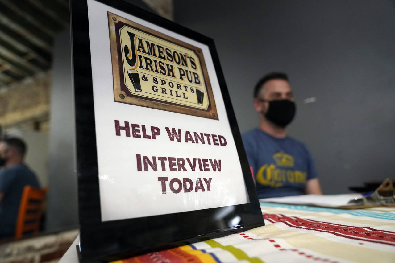 FILE - A hiring sign is shown at a booth for Jameson's Irish Pub during a job fair on Sept. 22, 202...