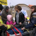 
              A Polish firefighter helping Ukrainian refugees, carries their belongings at border crossing in Medyka, southeastern Poland, on Wednesday, March 30, 2022. The U.N. refugee agency says more than 4 million people have now fled Ukraine following Russia's invasion, a new milestone in the largest refugee crisis in Europe since World War II. (AP Photo/Sergei Grits)
            