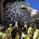 
              Los Angeles school children gather around a giant puppet porcupine named Percy at Elysian Park in Los Angeles on Tuesday, March 1, 2022. Percy, a two-story puppet emerged from its home for an audience of school children and media members at the Los Angeles park on Tuesday. The adorable beast with its massive pink nose inspired oohs and awwws. A joint project of the San Diego Zoo Wildlife Alliance Jim Henson's Creature Shop, Percy was let out to celebrate next week's opening of the zoo's new Wildlife Explorers Basecamp. (AP Photo/Richard Vogel)
            