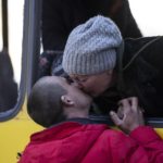 
              Mykolaivna Shankarukina, 54, kisses her son from inside a damaged bus as she is leaving from the Ukrainian Red Cross center in Mykolaiv, southern Ukraine, on Monday, March 28, 2022. Shankarukina and her family evacuated from Sablagodante village in the Mykolaiv district that have been attacked by the Russian army. She and a grandson are going to Odesa and from there to Prague, as the rest of the family, her son, daughter in law and a grandson will stay in Mykolaiv in a center for displaced residents. (AP Photo/Petros Giannakouris)
            