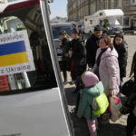 
              Ukrainian refugees with children board transport at a square next to a railway station in Przemysl, Poland, on Tuesday, March 22, 2022. (AP Photo/Sergei Grits)
            