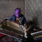 
              Zabiullah Nuri, 45, covers his face to protect his identity as he shows his harmonium musical instrument that Taliban fighters broke with their guns when he was carrying it home from his shop, in Kabul, Afghanistan, Sunday, Feb. 20, 2022. The songs are silent in the traditional musicians' quarter of Kabul's Old City, ever since the Taliban's takeover of Afghanistan six months ago. (AP Photo/Hussein Malla)
            