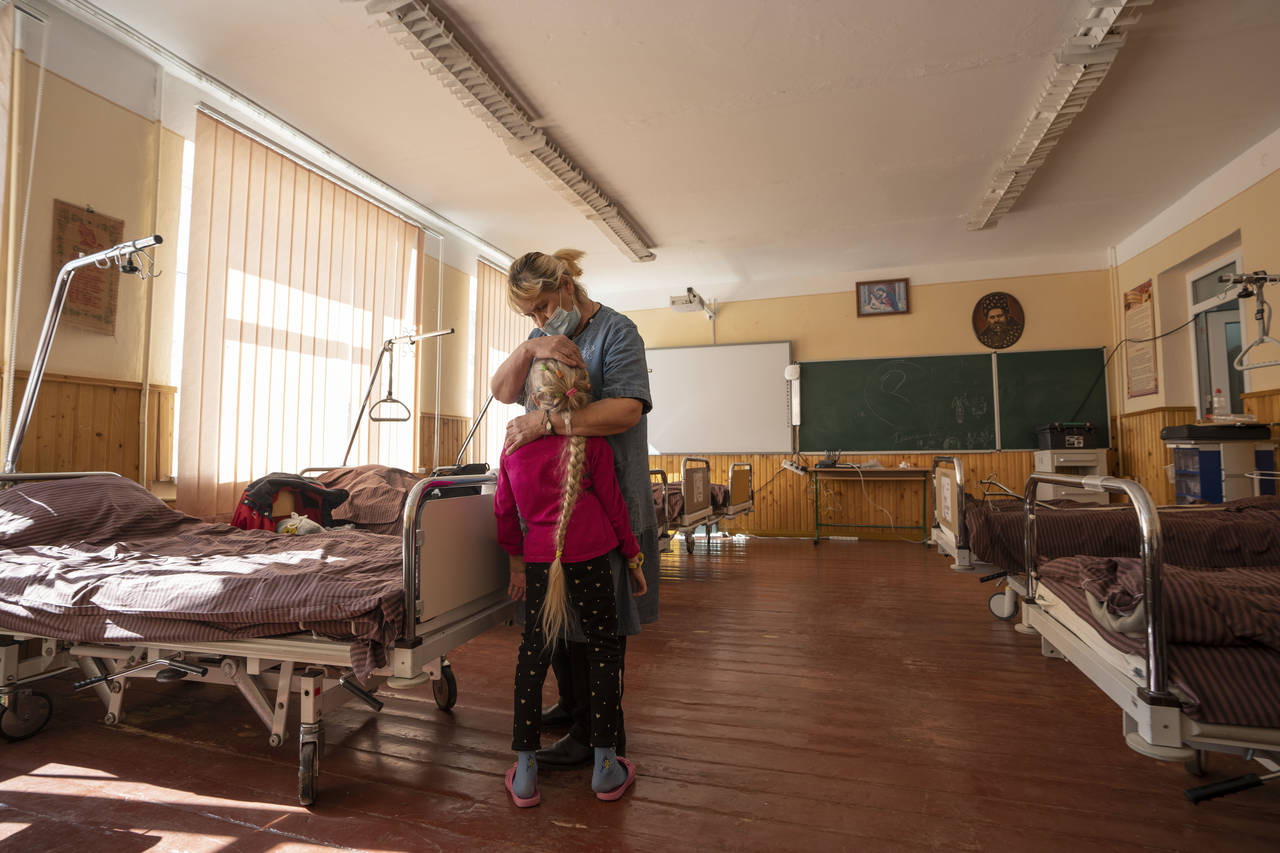 Nadia holds her 10-year-old granddaughter Zlata Moiseinko, suffering from a chronic heart condition...