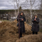 
              Vera Ptitsyna, 63, right, stands with her daughter Olena, 45, as she mourns on her husband's grave, Yuriy Ptitsyn, 74, who died due to lack of medical care during the monthlong Russian occupation of the town, during his funeral in Bucha, in the outskirts of Kyiv, Tuesday, April 19, 2022. (AP Photo/Emilio Morenatti)
            