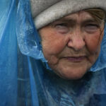 
              A woman walks during rain after fleeing the war from neighbouring Ukraine at the border crossing in Medyka, southeastern Poland, Saturday, April 9, 2022. (AP Photo/Sergei Grits)
            