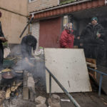 
              People cook on an open fire outside an apartment building which had no electricity, water or gas since the beginning of the Russian invasion in Bucha, Ukraine, Sunday, April 3, 2022. Associated Press journalists in Bucha, a small city northwest of Kyiv, saw the bodies of at least nine people in civilian clothes who appeared to have been killed at close range. At least two had their hands tied behind their backs.(AP Photo/Vadim Ghirda)
            