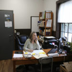 Victory Town Clerk Tracey Martel takes a phone call at the town clerk's office, in Victory, Vt., Thursday March 31, 2022. Martel says she's regularly frustrated watching a spinning circle on her computer while she tries to complete even the most basic municipal chores online. It could be years before high-speed internet reaches Victory. The need to connect homes and businesses to high-speed broadband services was highlighted by the COVID-19 pandemic and officials say that while there is lots of money available, supply and labor shortages are making the expansion a challenge. (AP Photo/Wilson Ring)
