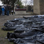 
              A family mourns a relative killed during the war with Russia, as dozens of black bags containing more bodies of victims are seen strewn across the graveyard in the cemetery in Bucha, in the outskirts of Kyiv, Ukraine, Monday, April 11, 2022. (AP Photo/Rodrigo Abd)
            