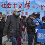 
              Residents wearing face masks to help protect from the coronavirus wait in line to get their throat swab at a coronavirus testing site near residential buildings, Wednesday, April 6, 2022, in Beijing. (AP Photo/Andy Wong)
            