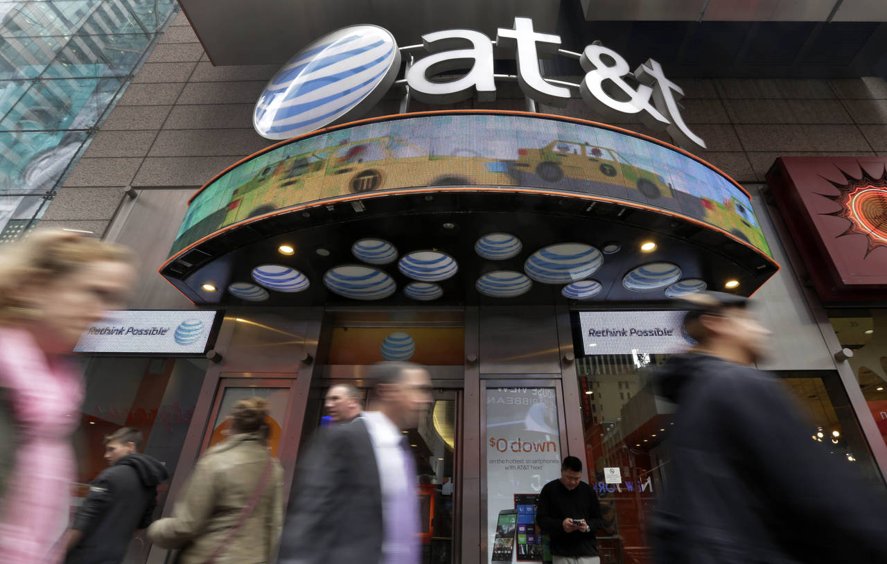 FILE - In this Oct. 21, 2014 file photo, people pass an AT&T store in New York's Times Square. Shar...