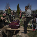 
              Cemetery workers during the funeral of Tetyana Gramushnyak, 75, killed by shelling on March 19 while cooking food outside her home in Bucha, in the outskirts of Kyiv, Ukraine, Thursday April 14, 2022. (AP Photo/Rodrigo Abd)
            