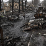 
              A woman walks amid destroyed Russian tanks in Bucha, in the outskirts of Kyiv, Ukraine, Sunday, April 3, 2022. (AP Photo/Rodrigo Abd)
            