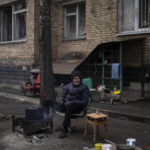 
              Russian Paramarchuk, 45, sits on a chair next to a makeshift fire outside his house destroyed by Russian shelling in Irpin, on the outskirts of Kyiv, on Thursday, April 21, 2022. Citizens of Irpin are still without electricity, water and gas after since the Russian invasion began. (AP Photo/Petros Giannakouris)
            