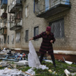 
              A woman looks for goods dropped from the apartment building partly damaged by shelling, in Kramatorsk, Ukraine, Thursday, April 14, 2022. (AP Photo/Andriy Andriyenko)
            