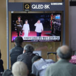 
              People watch a TV screen showing a news program reporting about North Korea's military parade with an image of North Korean leader Kim Jong Un and his wife Ri Sol Ju at a train station in Seoul, South Korea, Tuesday, April 26, 2022. North Korean leader Kim Jong Un vowed to move faster in bolstering his nuclear forces and threatened to use them if provoked in a speech he delivered during a military parade that featured powerful weapons systems targeting the country's rivals, state media reported Tuesday. (AP Photo/Lee Jin-man)
            