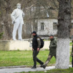 
              People pass a monument to Soviet Union founder Vladimir Lenin in Chernobyl, Ukraine, Saturday, April 16, 2022. Thousands of tanks and troops rumbled into the forested exclusion zone around the shuttered Chernobyl nuclear power plant in the earliest hours of Russia’s invasion of Ukraine in February, churning up highly contaminated soil from the site of the 1986 accident that was the world's worst nuclear disaster. (AP Photo/Efrem Lukatsky)
            