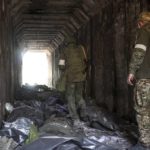 
              FILE - Servicemen of the Donetsk People's Republic militia look at bodies of Ukrainian soldiers placed in plastic bags in a tunnel, part of the Illich Iron & Steel Works Metallurgical Plant, the second largest metallurgical enterprise in Ukraine, in an area controlled by Russian-backed separatist forces in Mariupol, Ukraine, Monday, April 18, 2022. On Thursday, April 21, 2022, Russian President Vladimir Putin ordered his forces not to storm the last remaining Ukrainian stronghold in the besieged city of Mariupol but to block it “so that not even a fly comes through.”  (AP Photo/Alexei Alexandrov, File)
            