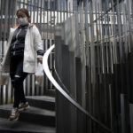 
              A woman wearing a face mask walks down a staircase at a shopping and office complex in Beijing, Wednesday, April 13, 2022. Shanghai has released more than 6,000 more people from medical observation amid a COVID-19 outbreak, the government said Wednesday, but moves to further ease the lockdown on China's largest city appeared to have stalled. (AP Photo/Mark Schiefelbein)
            