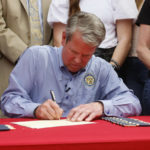 
              Gov. Brian Kemp signs a bill which will allow permit less carry at a sporting goods store in Douglasville, Ga., on Tuesday, April 12, 2022. SB 319 allows a "lawful weapons carrier" to carry a concealed handgun everywhere license holders currently are allowed. (Bob Andres/Atlanta Journal-Constitution via AP)
            